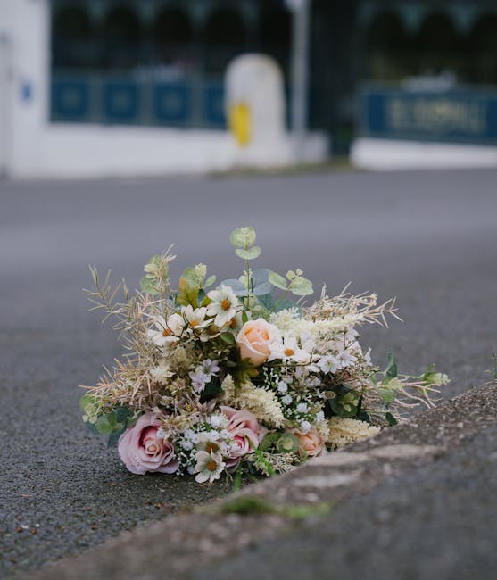 A delicate floral tribute consisting of soft pink roses, white daisies, and light green foliage arranged in a loose, natural style. The bouquet features a mix of fresh petals with subtle textures, inc