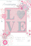 This anniversary card exudes a sense of gentle, enduring romance, reminiscent of a peaceful afternoon spent wandering the green stretches of Hackney Marshes. Dominating the centre is the word LOVE, spelled out in soft, raised lettering dusted with fine glitter, each curve and edge catching light with a refined, pearlescent sparkle. The colour palette leans into dreamy blush pinks, warm whites, and understated silvery greys, creating an atmosphere that feels both intimate and celebratory. Around this central word, a constellation of delicate blossoms and sweeping vines flows outward, their shapes drawn with the precision and creativity of a seasoned florist arranging a romantic anniversary bouquet. The flowers appear in gentle shades of blush and pale mauve, with slender leaves that curl gracefully, some kissed with silver accents that glint like the canals bordering the marshland. The background is a soft, powdery pink that supports the design without overwhelming it, giving every detail space to breathe. Subtle flourishes-tiny petals, gentle swirls, and finely traced stems-add motion and lightness, as if a soft breeze were passing over a field of flowers. An affectionate message, including sentiments such as On Our Anniversary or I love you today and always, is written in an understated, elegant script that blends beautifully with the floral motif. The combination of tactile glitter, soft colour, and thoughtful typography makes this card feel like a hand-crafted tribute to shared love, ideal for an anniversary celebration at home after a slow, reflective walk through Hackney Marshes.
